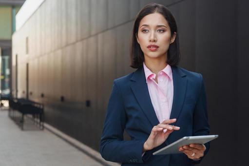 街なかでタブレットを使っているビジネスウーマン ビジネスウーマン,ビジネス,女性の写真素材