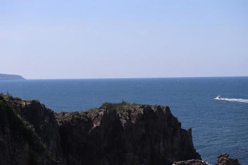 岩壁と船のゆく青い海と水平線と青空の風景 岩壁と船のゆく青い海と水平線と青空の風景の写真
