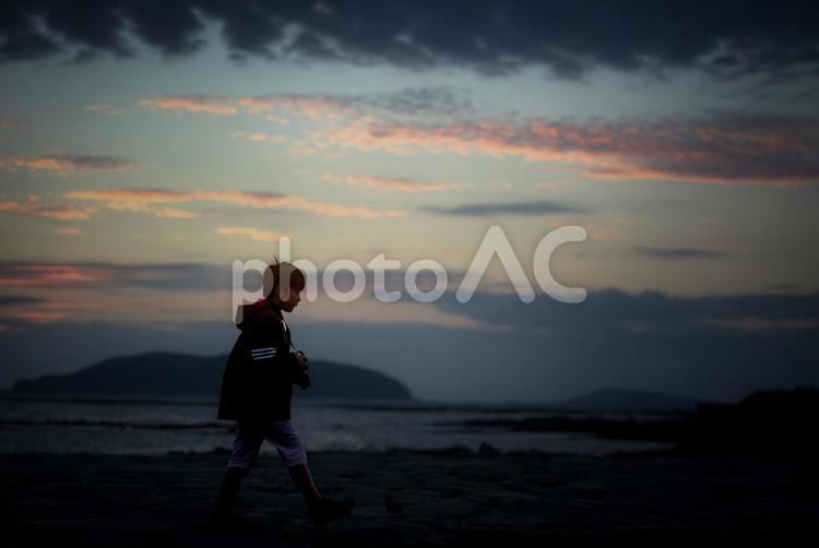 R＜素材＞夕暮れの海を歩く小学生写真家 子供,海,散歩の写真素材