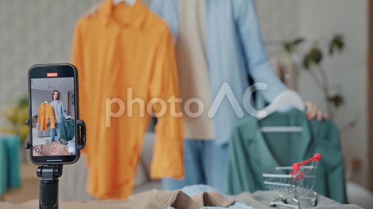 オレンジ色のシャツを持っている男性を配信している画面 画面,人物,撮影の写真素材