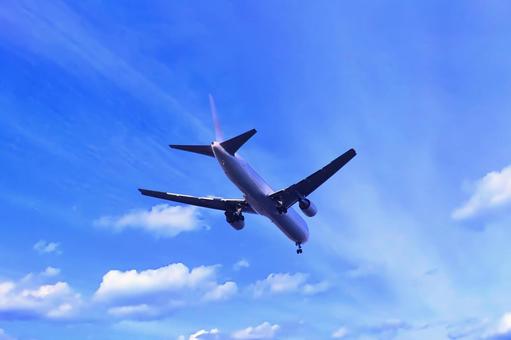着陸態勢のジェット旅客機と秋の青空の写真