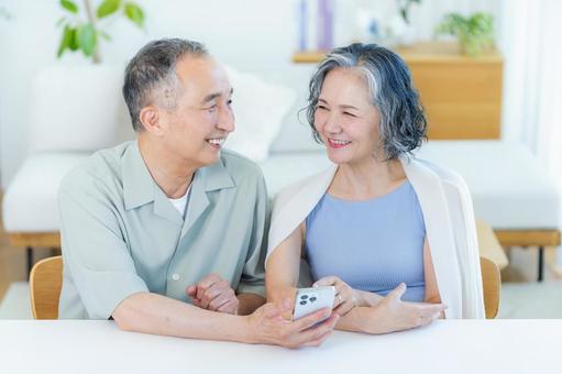 リビングでスマホを見るシニア夫婦 リビングでスマホを見るシニア夫婦 スマホ,笑顔,シニアの写真素材