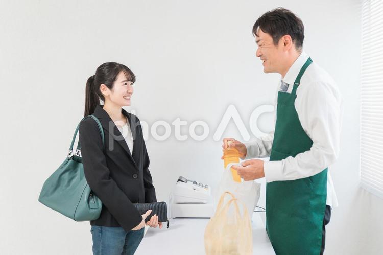笑顔でお弁当を買う女性と話すコンビニ店員 レジ,コンビニ,お弁当の写真素材