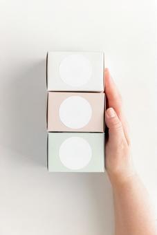 A hand touching three boxes with round labels (white background), mock up, female, hand, JPG