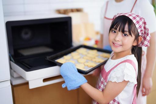 オーブンからクッキーを出す笑顔の女の子 女の子,日本人,クッキーの写真素材