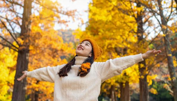紅葉の中で深呼吸する秋服の日本人女性 紅葉の中で深呼吸する秋服の日本人女性の写真