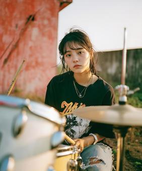 廃工場を背景にドラムを叩く女性 廃工場を背景にドラムを叩く女性の写真