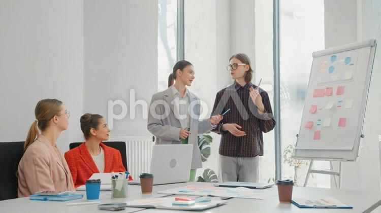 付箋を貼ったホワイトボードの前で話し合いをしている男女4人 ビジネス,ビジネスマン,ビジネスウーマンの写真素材