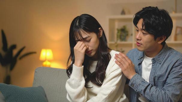 落ち込む彼女と、なぐさめる彼氏の写真