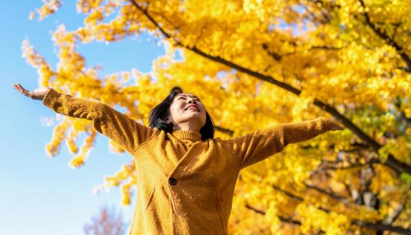 秋の紅葉を楽しみながら公園を散歩する女性 秋の紅葉を楽しみながら公園を散歩する女性の写真