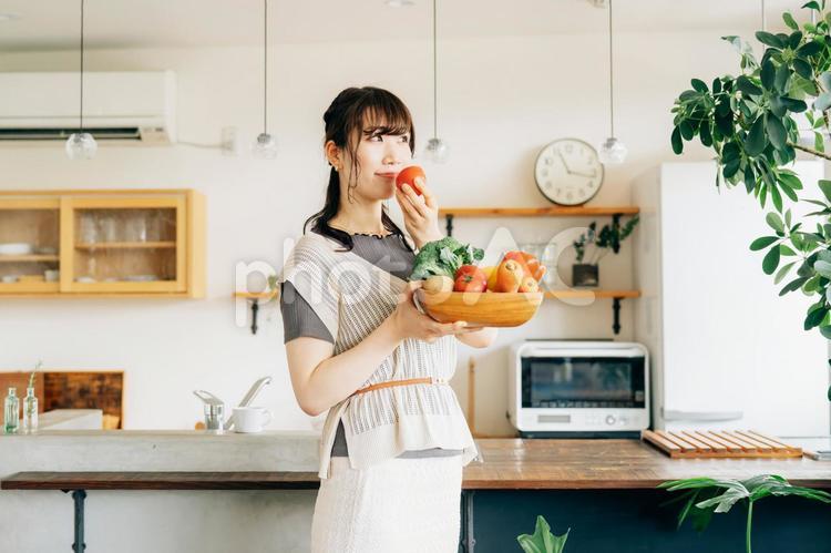 キッチンの前に野菜を持つ女性（トマト） 野菜,トマト,女性の写真素材