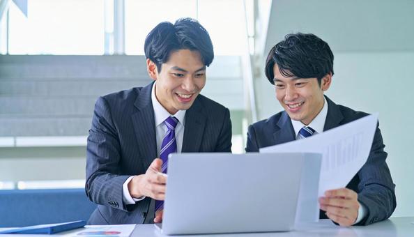 パソコンと資料を見ながら相談する社員の写真