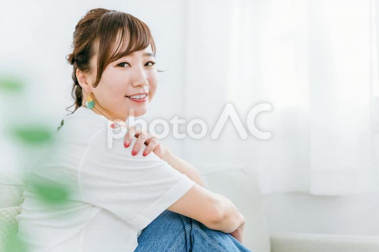 家のソファに座るジーンズ姿の日本人女性 ソファ,女性,リラックスの写真素材
