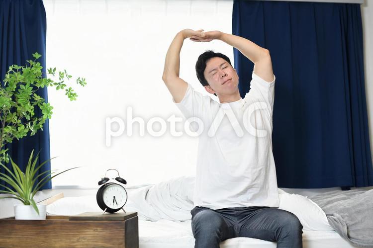 起床後にベッドの上でストレッチをする男性 ベッド,起床,男性の写真素材