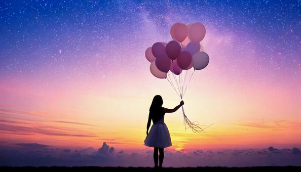夕焼け空と風船を持つ少女 夕焼け空と風船を持つ少女の写真