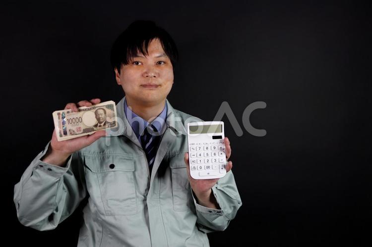 作業服の男性が札束と電卓を持つ 作業員,作業服,男性の写真素材
