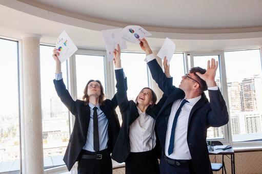 手を伸ばし書類を持つ笑顔の男女の写真