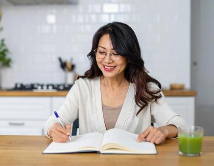 テキストを開きノートに書く日本人女性 テキストを開きノートに書く日本人女性の写真