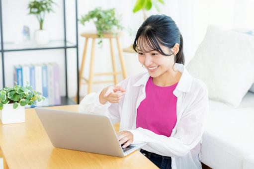 自宅でノートパソコンを操作する若い女性 若い女性,ノートパソコン,笑顔の写真素材