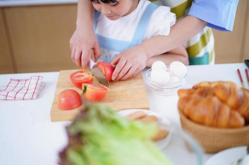 トマトを一緒に切る親子の手元 トマト,野菜,包丁の写真素材