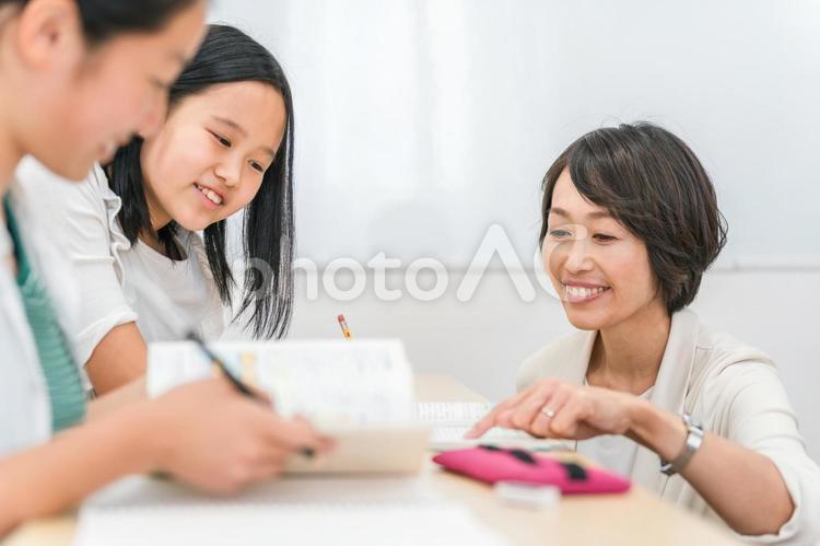 先生に質問する小学生の女の子と女性講師 小学校,授業,勉強の写真素材
