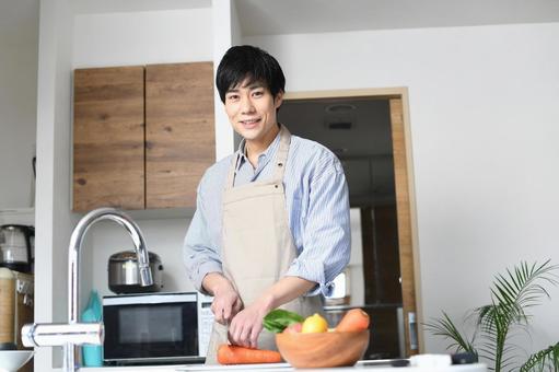 A young black-haired man in an apron cooking in the kitchen, wong lanang, masak, pawon, JPG