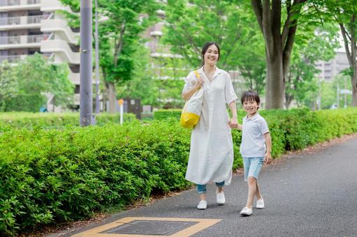 手を繋いで屋外を散歩する親子 手を繋いで屋外を散歩する親子の写真