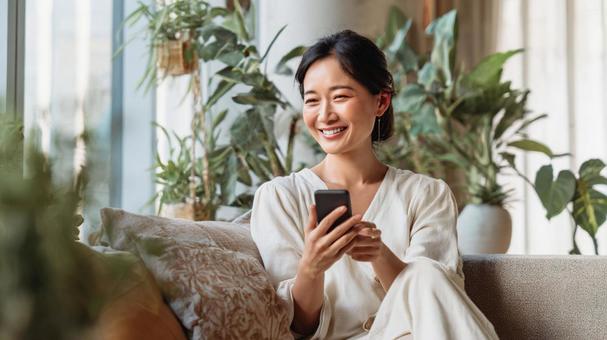 笑顔でスマホを見る女性の写真