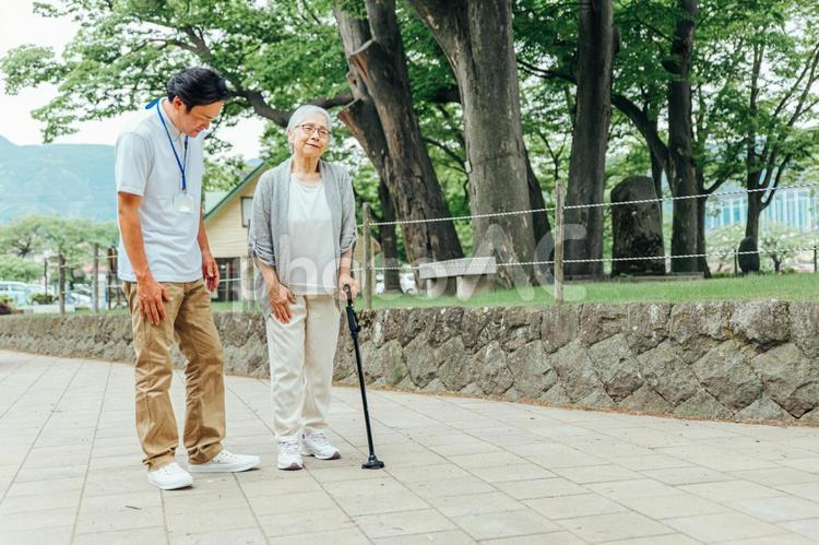 高齢者をサポートする男性スタッフ（杖） 介護士,リハビリテーション,理学療法士の写真素材