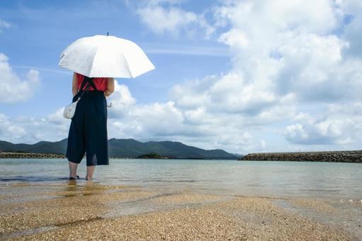 ＜素材＞夏の海の砂浜で海を眺める女性 女性,日傘,青空の写真素材