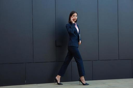 オフィスビルの外で歩きながら電話するビジネスウーマン ビジネスウーマン,ビジネス,女性の写真素材