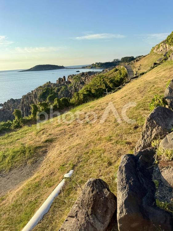 夏の夕方の福井県東尋坊と雄島 太陽,雄島,さざ波の写真素材