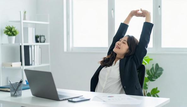 仕事が終わり達成感で背伸びをする社員 仕事が終わり達成感で背伸びをする社員の写真