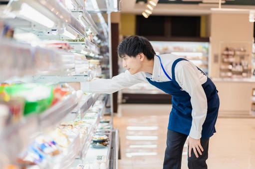 食品スーパーで品出しをする若いスタッフ 棚,カウント,コピースペースの写真素材
