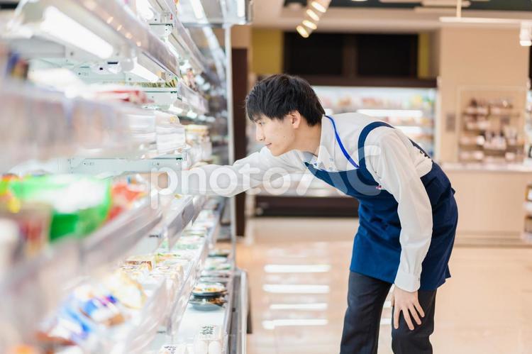 食品スーパーで品出しをする若いスタッフ 棚,カウント,コピースペースの写真素材