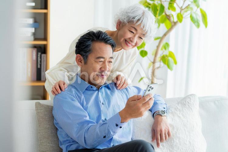 リビングでスマホを見るシニア夫婦 シニア,夫婦,スマホの写真素材