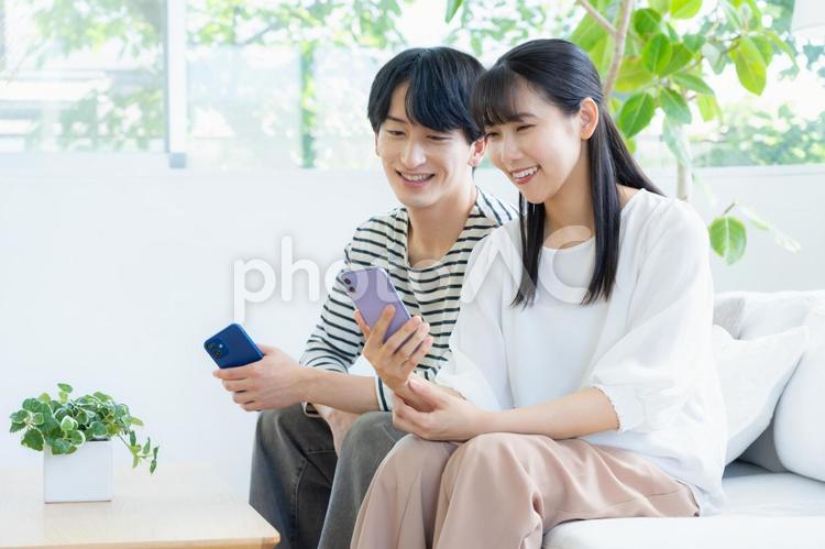 リビングでスマホを見る若いカップル 夫婦,カップル,リビングの写真素材