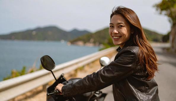 休日に海辺をバイクでツーリングする女性 休日に海辺をバイクでツーリングする女性の写真