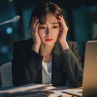 疲労困憊のオフィスワーカー頭を抱える女性 疲労困憊のオフィスワーカー頭を抱える女性の写真