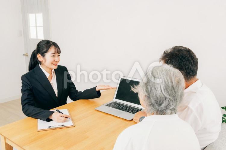 PCで説明するスーツ姿の女性と高齢者夫婦 相談,税理士,司法書士の写真素材