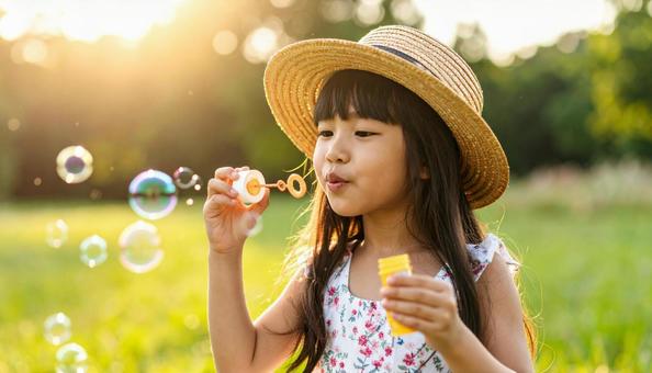 夏の日差しの中でシャボン玉を吹く女の子 夏の日差しの中でシャボン玉を吹く女の子の写真
