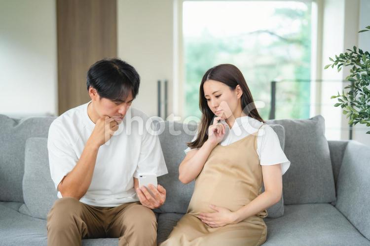 スマホを見る妊婦と男性（悩む） 妊婦,妊娠,夫婦の写真素材
