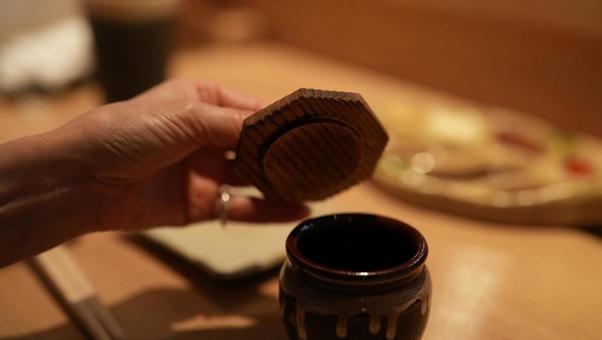 飲食店でうめぼしのツボのふたを開ける女性 飲食店でうめぼしのツボのふたを開ける女性の写真