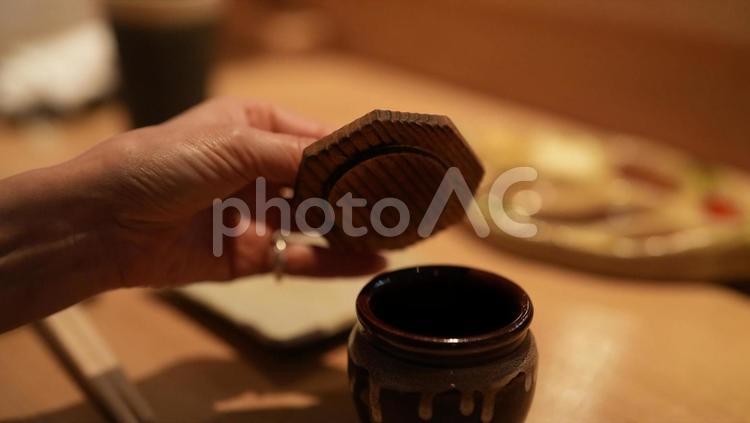 飲食店でうめぼしのツボのふたを開ける女性 女性,手,指の写真素材