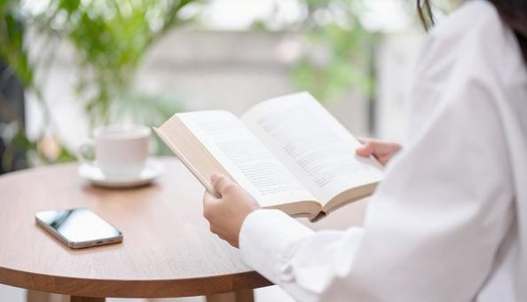 カフェで読書する女性の手元アップ カフェで読書する女性の手元アップの写真