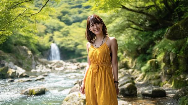 夏の渓流沿いの遊歩道に立つ若い日本人女性 夏の渓流沿いの遊歩道に立つ若い日本人女性の写真