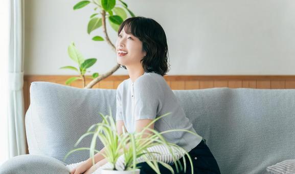 リビングのソファに座る笑顔の女性 リビングのソファに座る笑顔の女性の写真