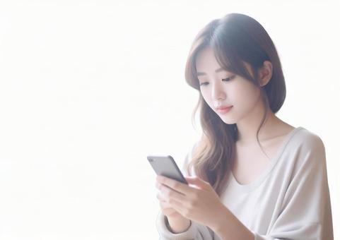 【透過】明るい自然光の中スマホを見る女性 【透過】明るい自然光の中スマホを見る女性の写真