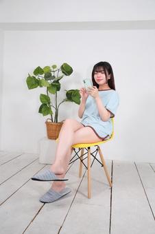 部屋着でスマートフォンを操作する女性 部屋着でスマートフォンを操作する女性の写真