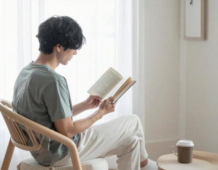 自宅の椅子で読書をする男性 自宅の椅子で読書をする男性の写真